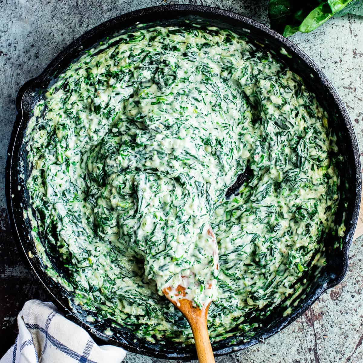 creamed spinach in a black skillet.