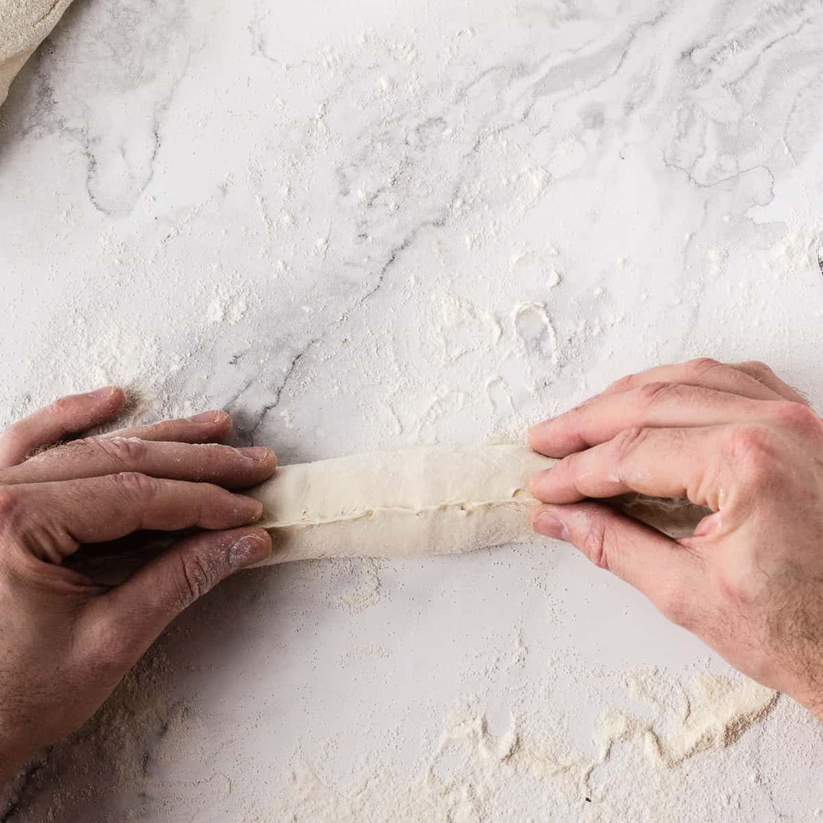 Pinching baguette seem closed with fingers.