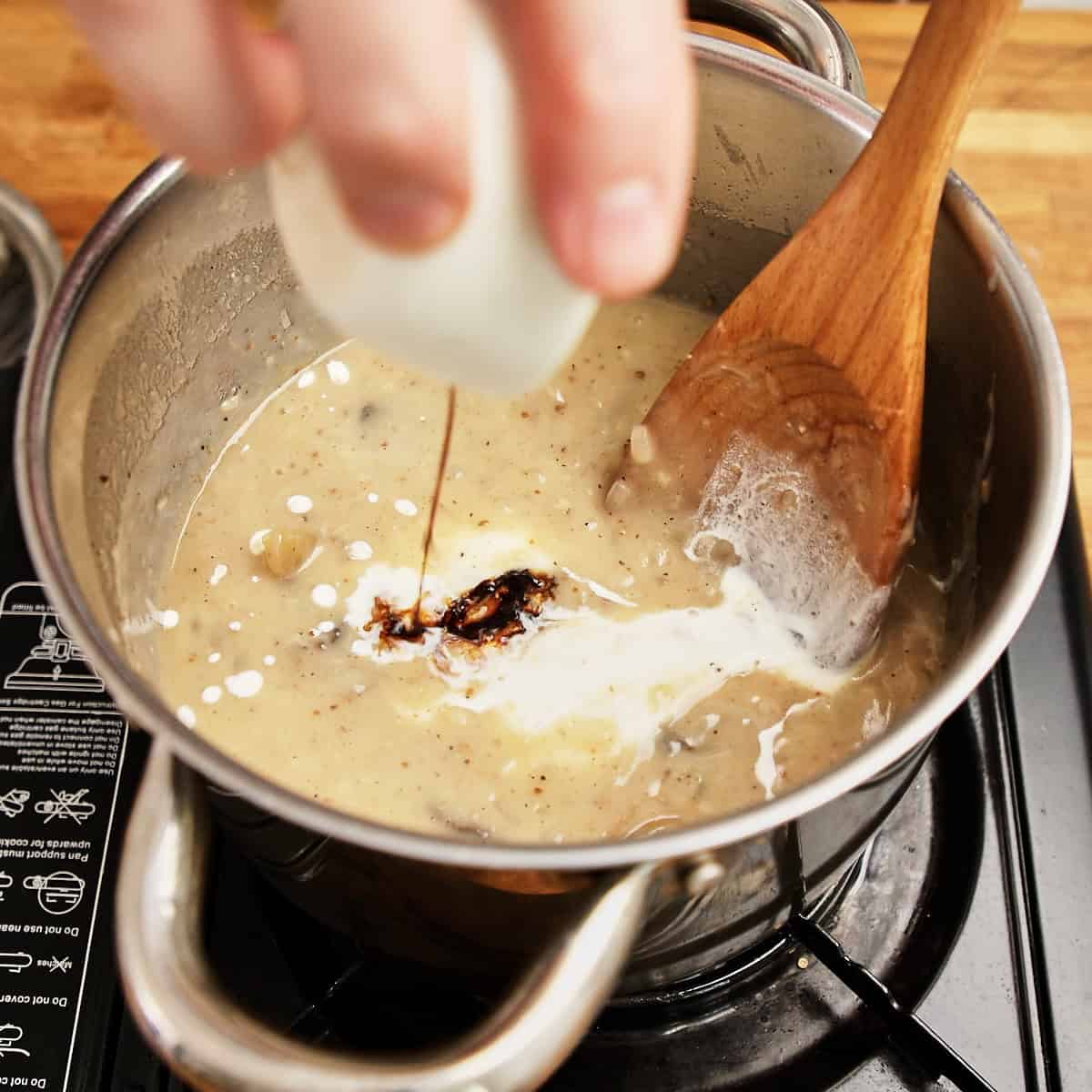 Cream poured into simmering biltong soup with sliced biltong visible.