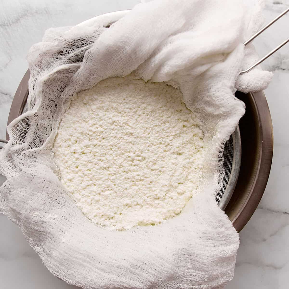 Cheese curds draining in a cheese cloth.