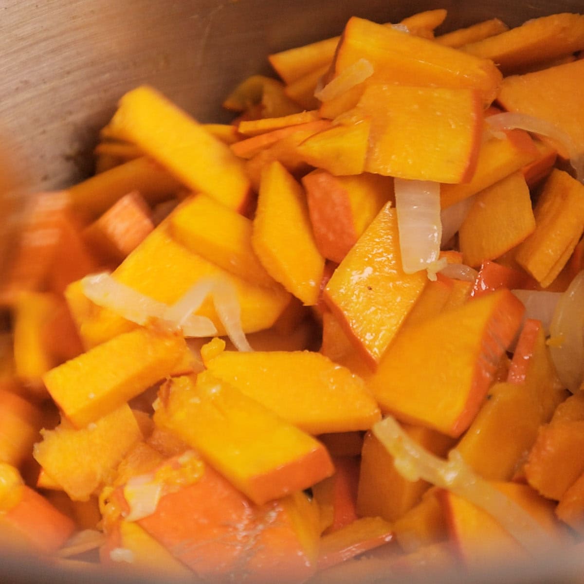 Sautéing pumpkin and onions in a pan.