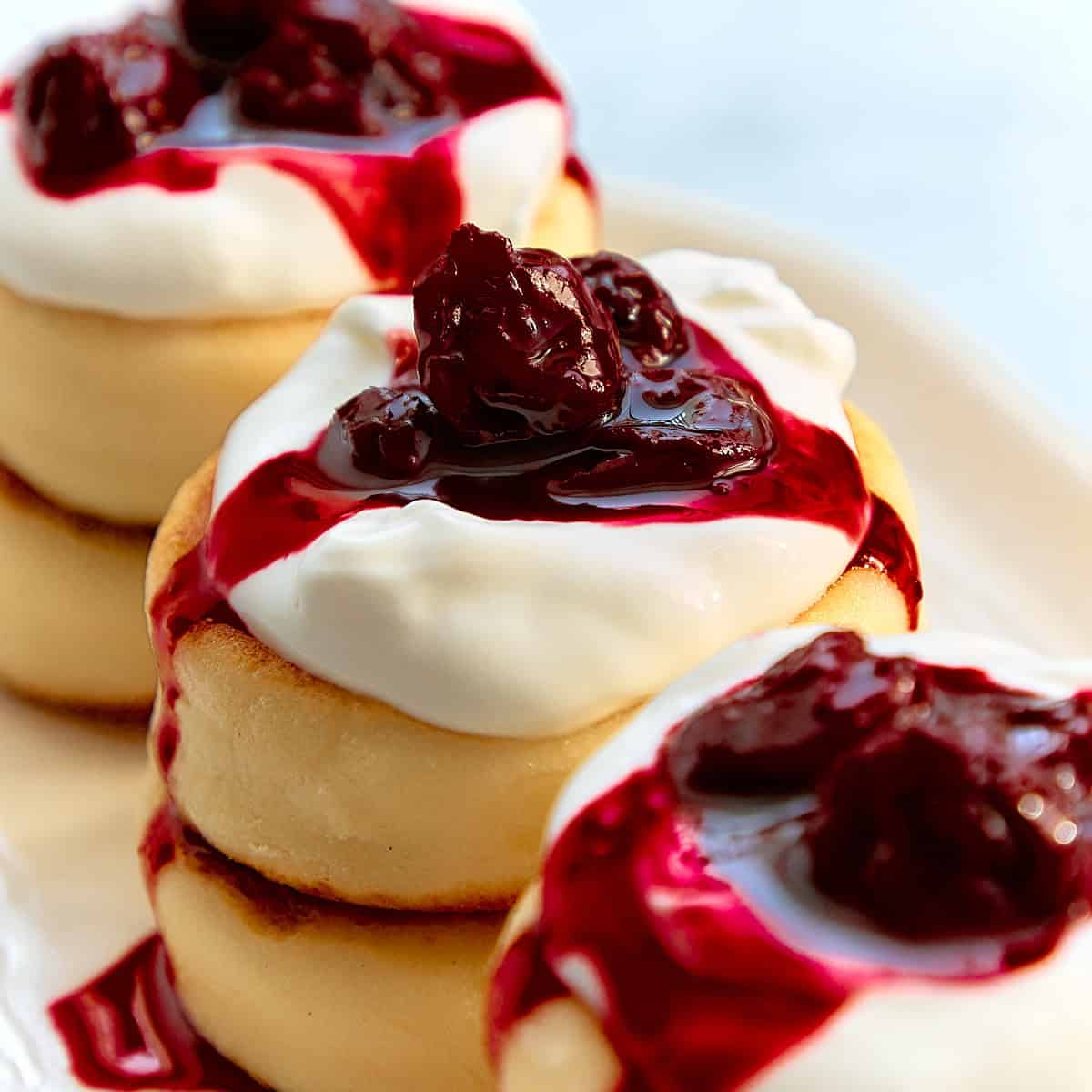 Syrniki cheese pancakes with cherry jam on a white plate.