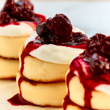 Syrniki cheese pancakes with cherry jam on a white plate.