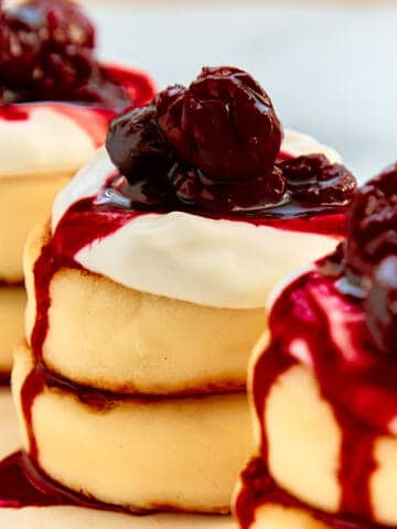 Syrniki cheese pancakes with cherry jam on a white plate.