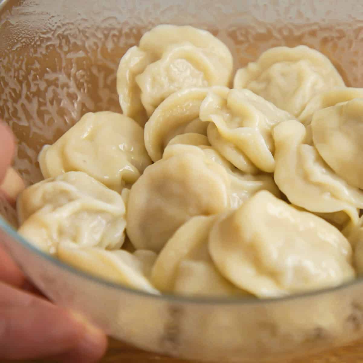 Tossing cooked pelmeni in butter.