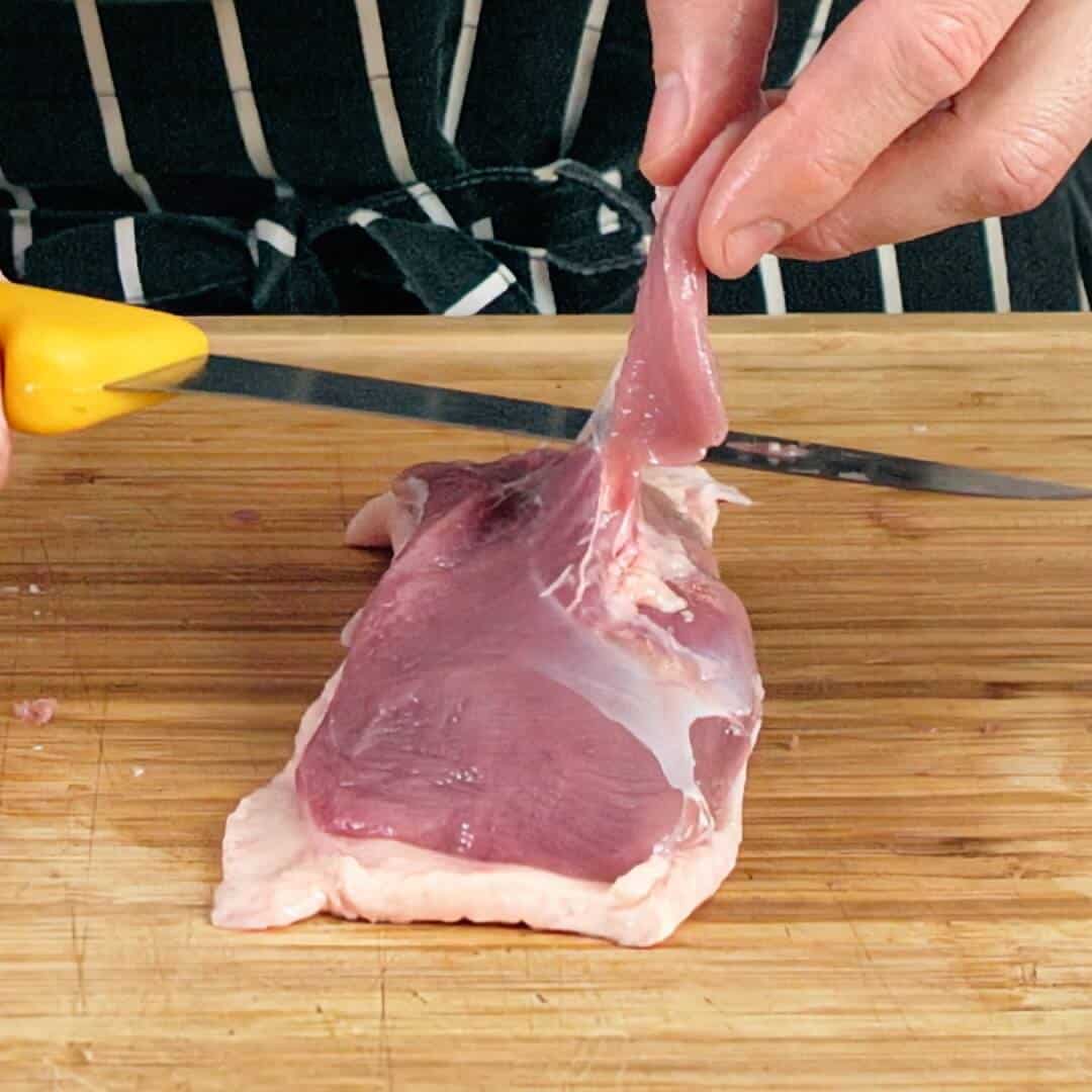 Cleaning a duck breast with a knife.