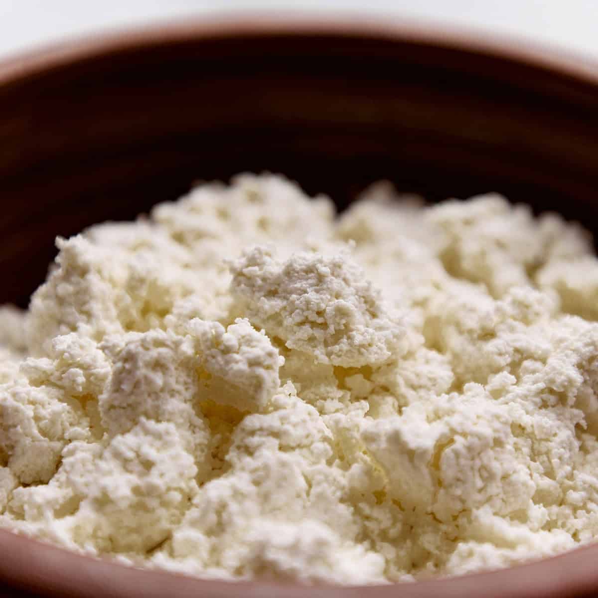 Cheese curds, farmer's cheese or tvorog in a brown bowl. 
