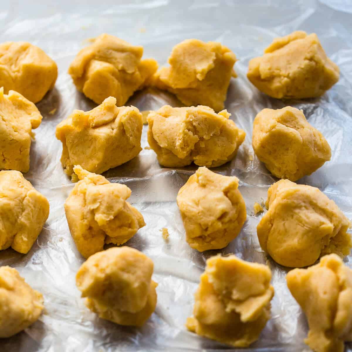 Individual cookie dough pieces on a parchment lined tray.