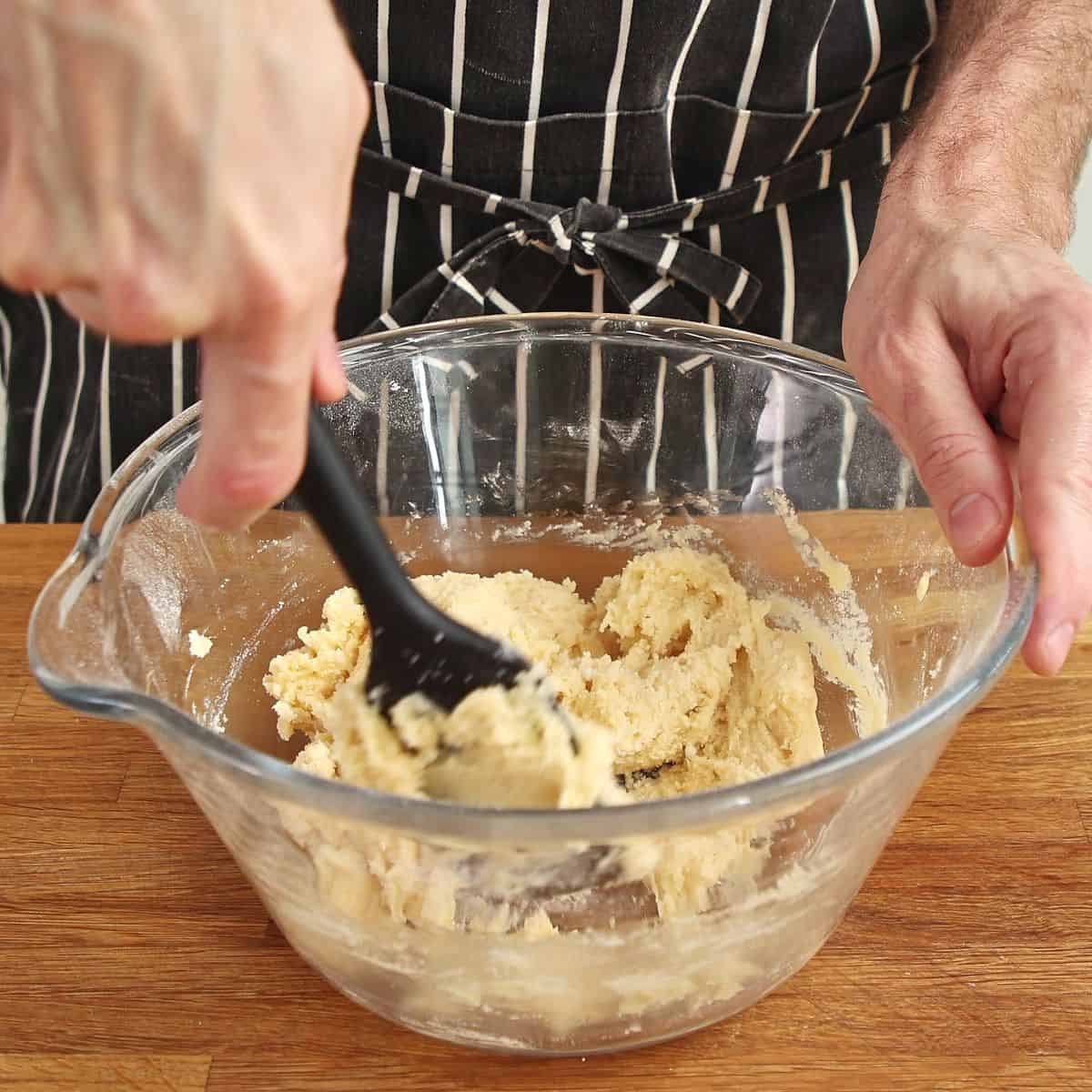 Wet ingredients being added to dry mixture, fork beginning to bring dough together, showing shaggy sticky texture