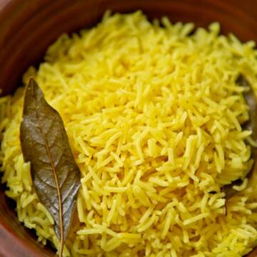 Yellow rice in a brown ceramic bowl.