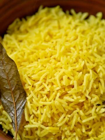 Yellow rice in a brown ceramic bowl.